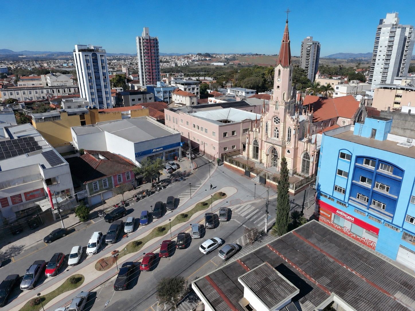 Vista aérea mais aberta: o conjunto entre o Santuário do Coração de Maria e a Praça João Pinheiro, no centro de Pouso Alegre.